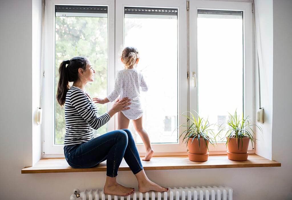 Mutter mit ihrer kleinen Tochter schaut aus dem Fenster